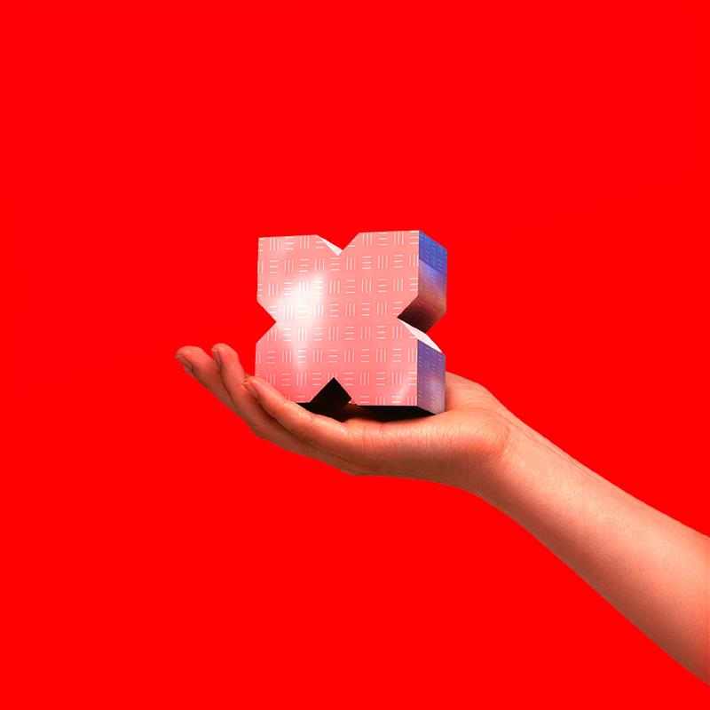 Image of a hand holding a chrome x with a red background.